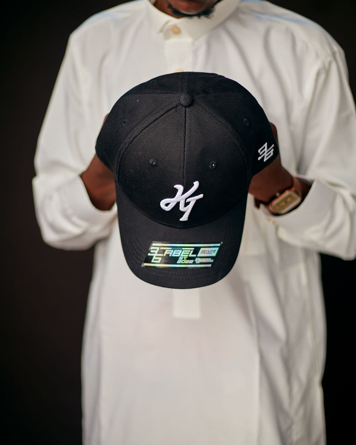 A Threads by RZN cap held against a white tee